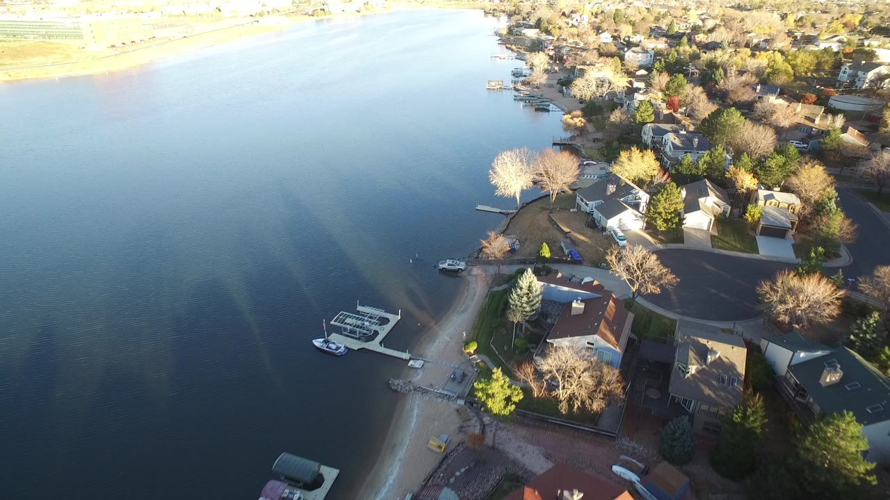 Aerial view of lakefront homes, docks, roads, and trees.