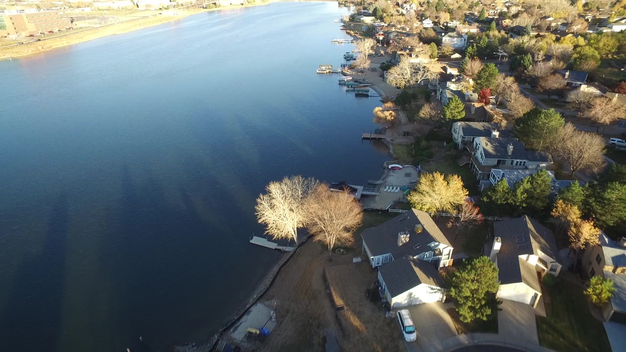 Aerial view of open water beside houses, docks, and trees.