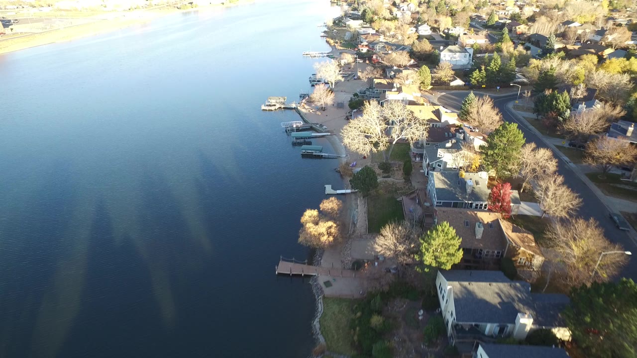 Aerial view of blue water beside shoreline homes and docks.