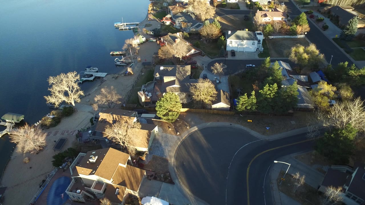 Aerial view of lakeside homes and curved neighborhood streets.