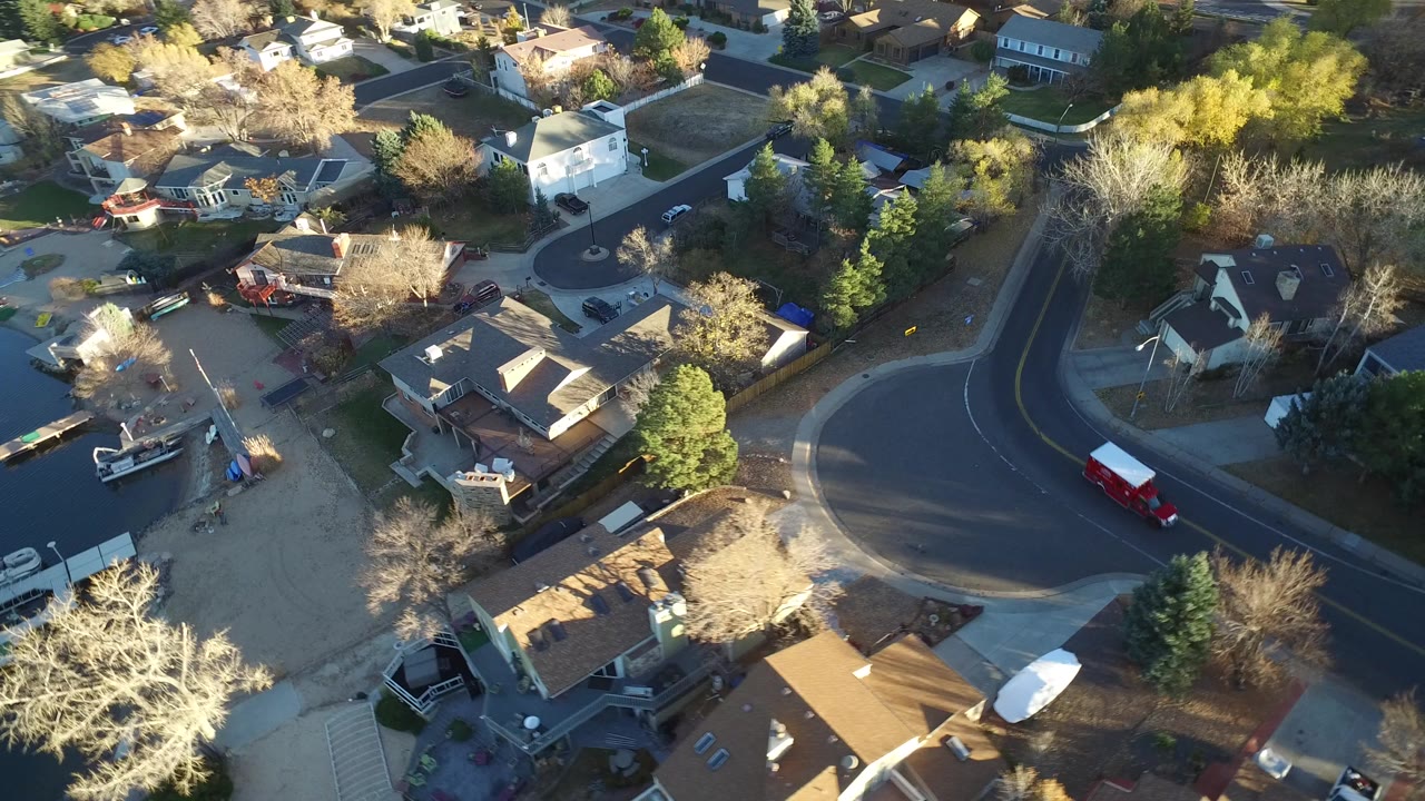 Aerial view of suburban homes beside a curved street and water.