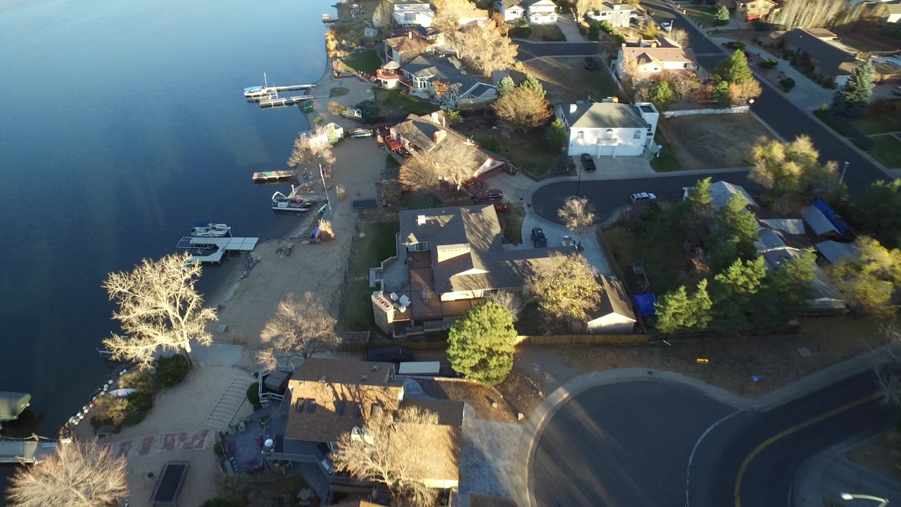 Aerial view of lakefront suburban houses with docks and trees.