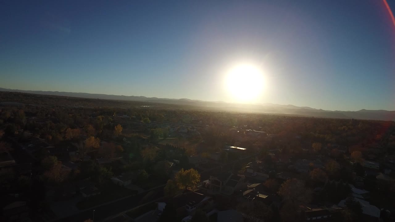 Low sun over a dark suburban landscape and distant hills.