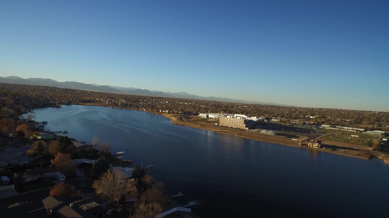 Aerial view over a lake beside suburban homes and low-rise buildings.