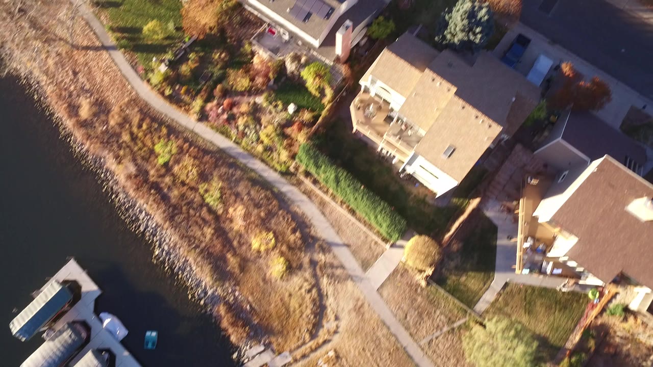 Aerial view of homes beside a curved path and water edge.