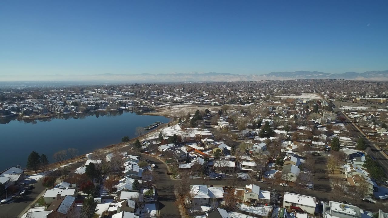 Aerial view of a lake beside snow-dusted residential homes.