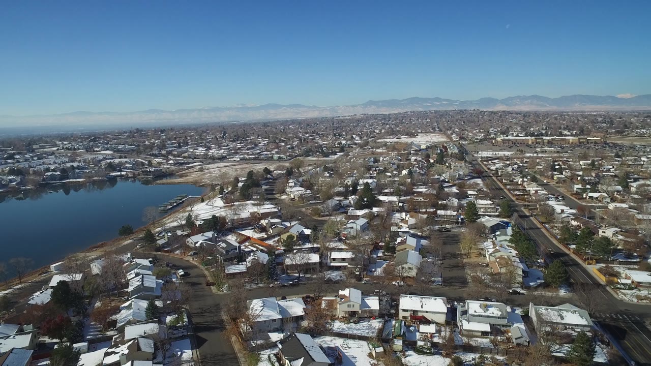 Aerial view over Hidden Lake, Colorado, with foreground houses, bare winter trees, a broad lake edge at left, and no visible people.
