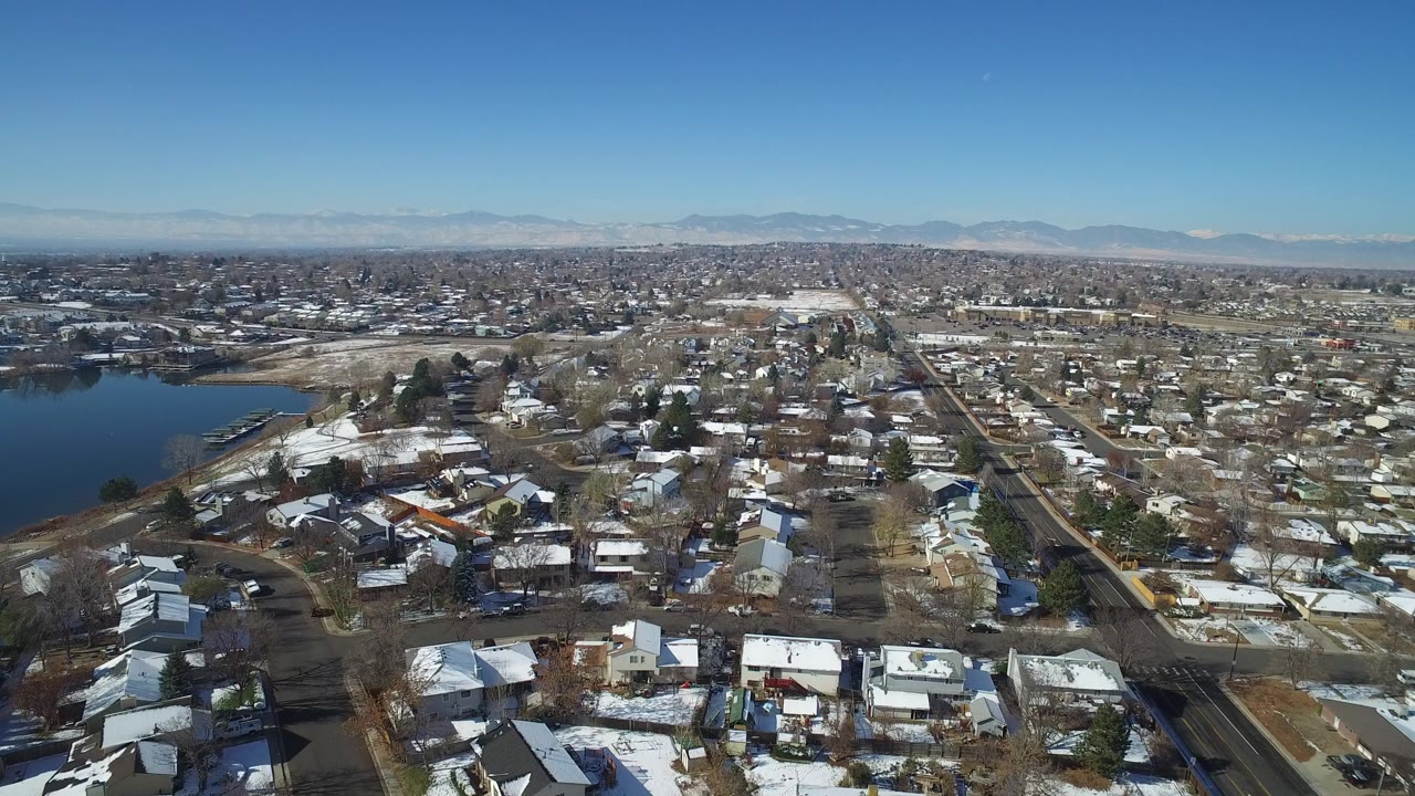 Aerial view of suburban houses beside a lake with distant mountains.