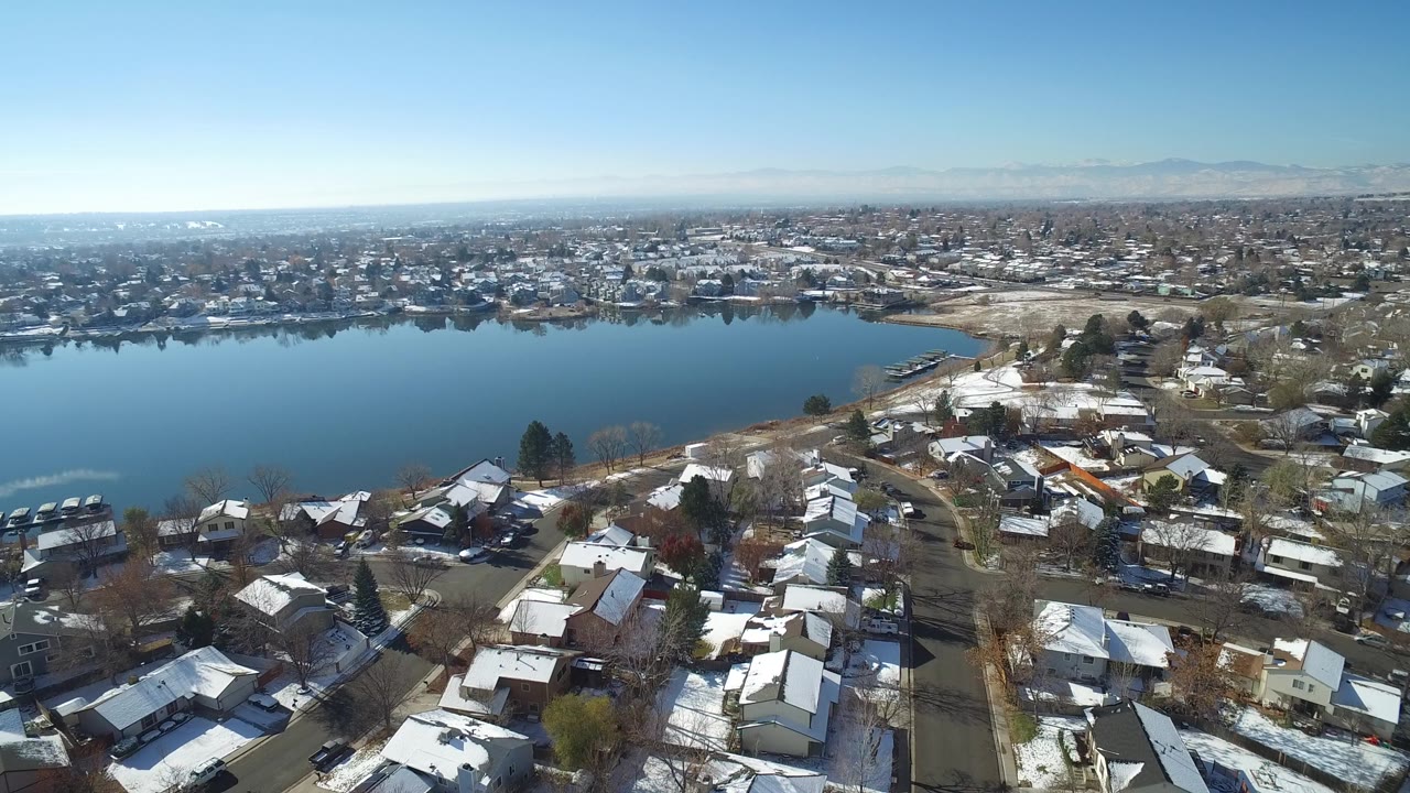 Aerial view of homes beside a blue lake under clear sky.