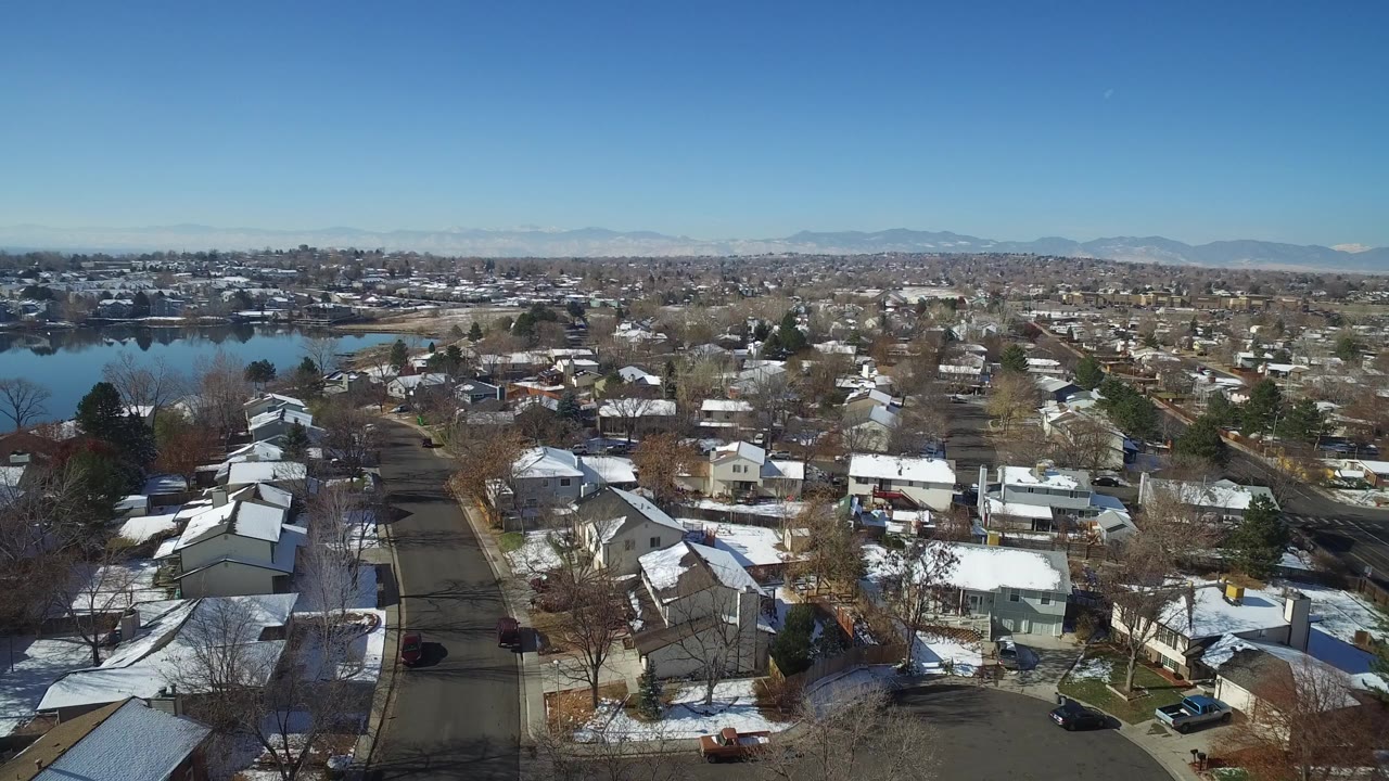 Aerial view over snow-dusted suburban houses and a residential street.