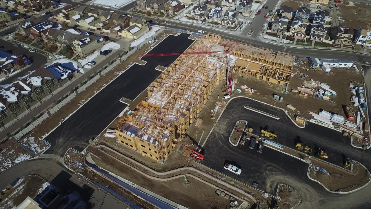 Aerial frame of a partially built residential complex with equipment and surrounding streets.