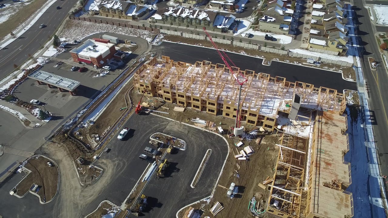 Aerial view of construction framing near a road junction and residential homes.