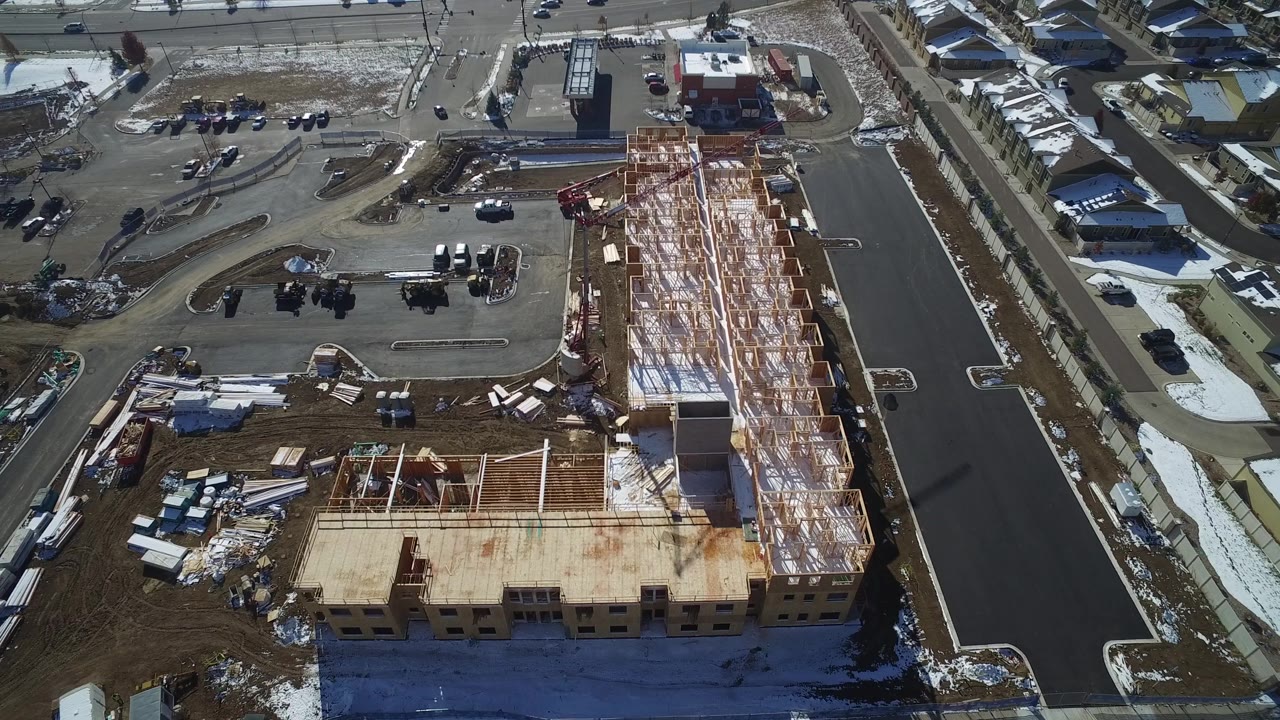 Drone view of a large building under construction near a residential block.