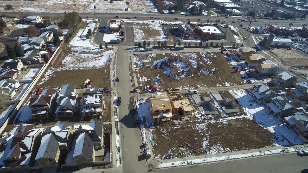 Aerial frame over Hidden Lake, Colorado with a curved residential road, clustered homes, unfinished construction areas, patchy snow, and no visible people.