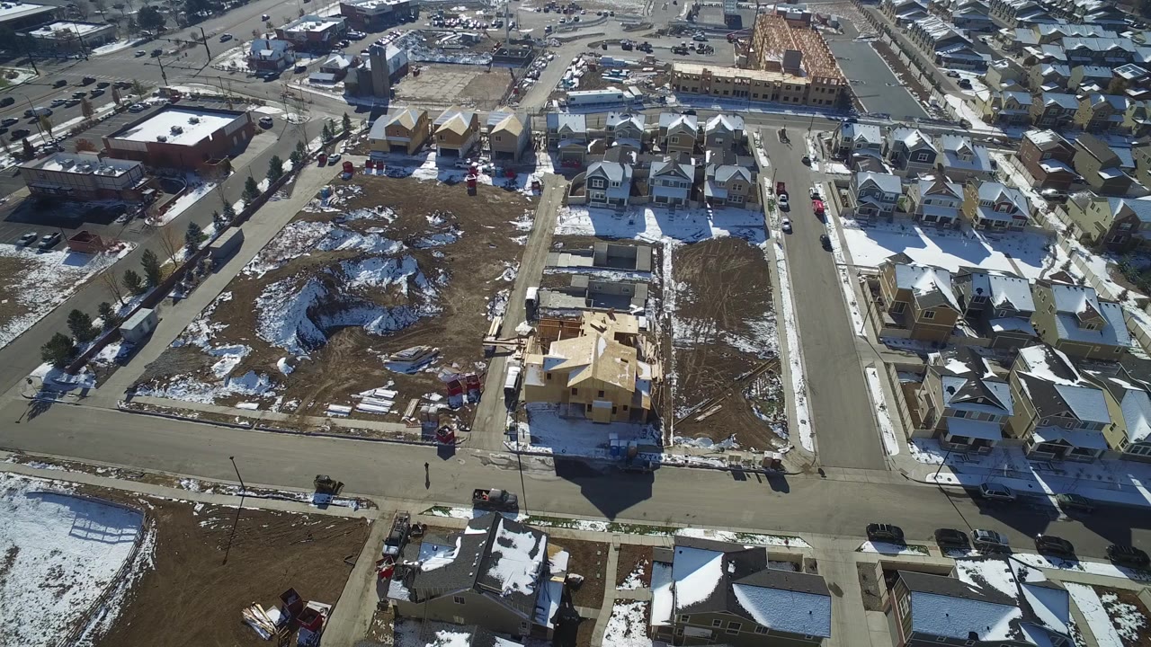 Aerial view of residential streets, houses, snow patches, and construction lots.