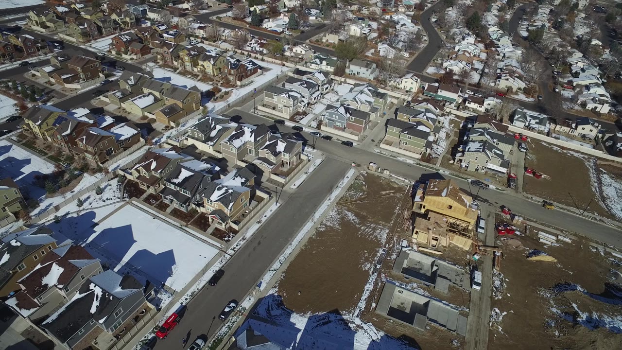 Hidden Lake, Colorado appears from above with a central road intersection, snow patches on roofs and lawns, parked vehicles, and a partly built house in the lower right with no visible people.