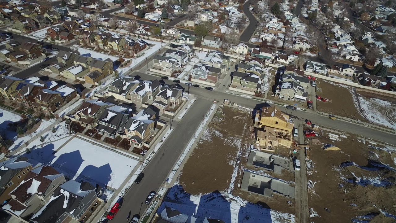 Overhead neighborhood view with vacant lots, houses, and a framed building.