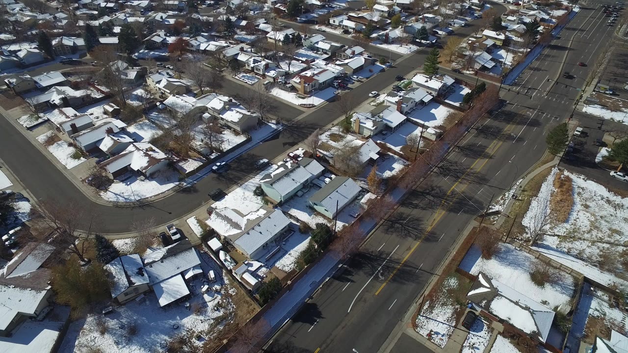 Aerial view of snow-dusted houses beside a multi-lane road.