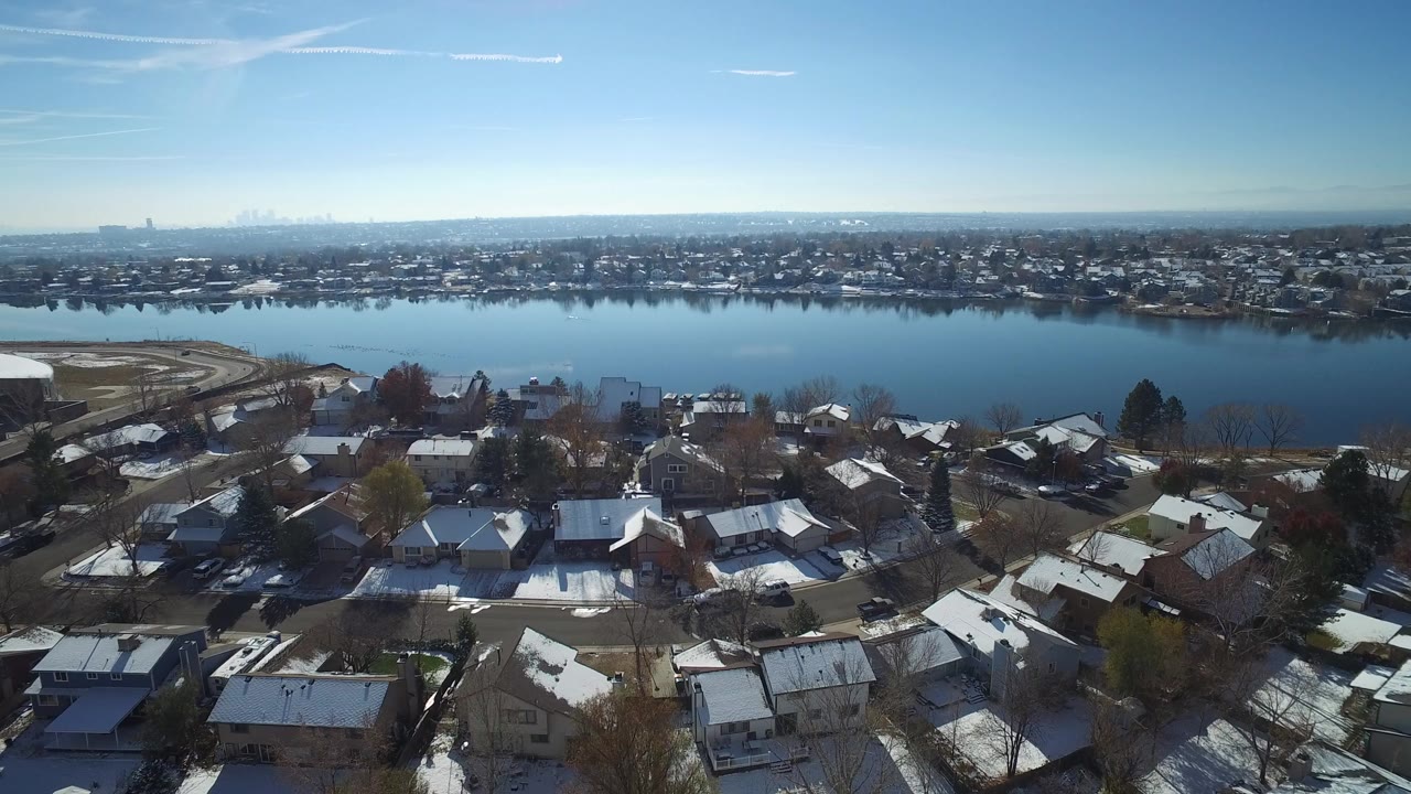 Aerial view over snowy rooftops beside a wide lake