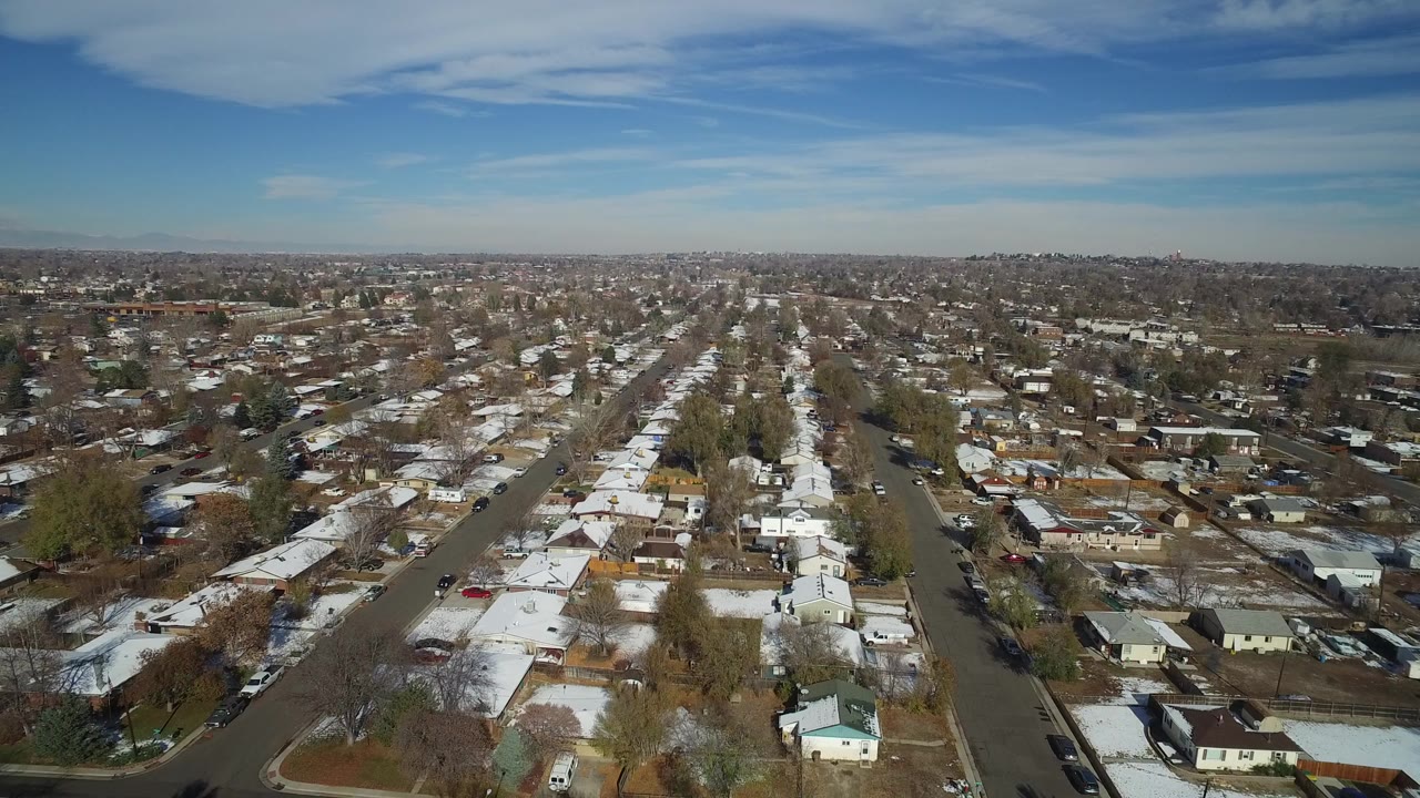 Aerial view over a suburban neighborhood with snow-dusted roofs and gridded streets.