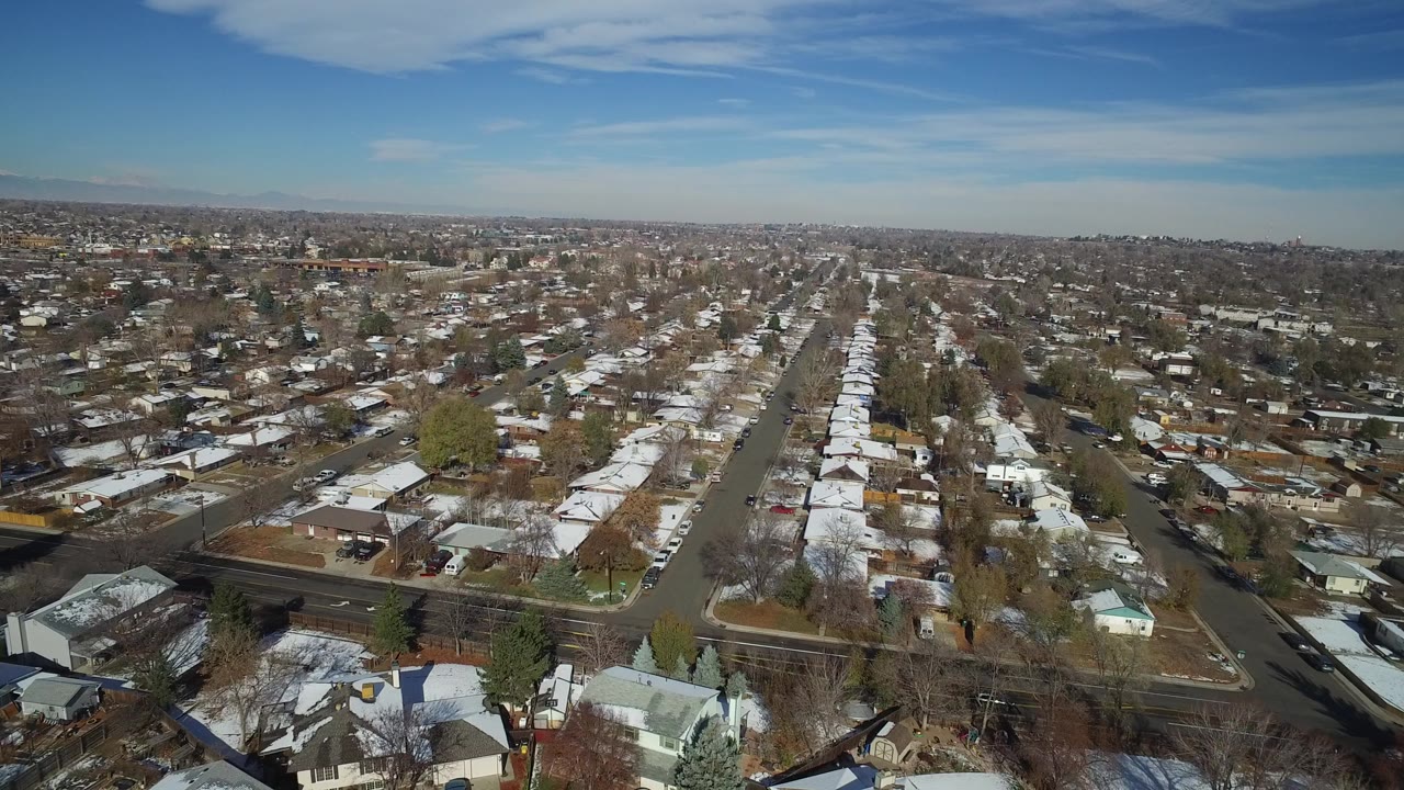 Aerial view over snow-dusted suburban houses and streets.