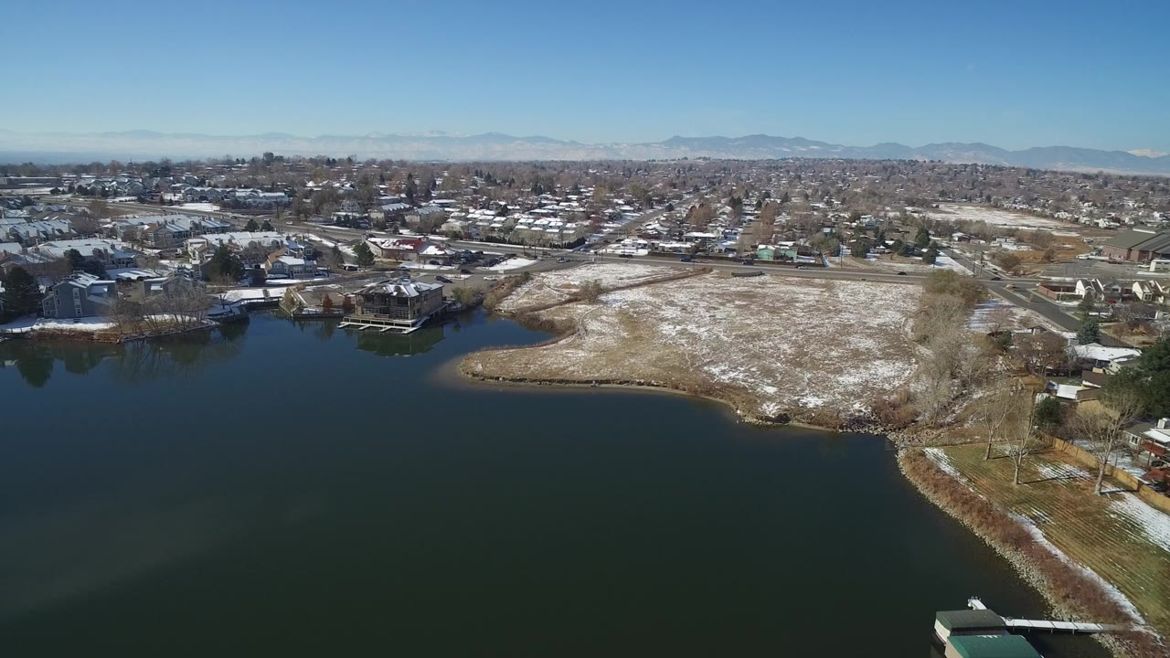 Aerial view of dark lake water beside a snow-dusted shoreline and town.