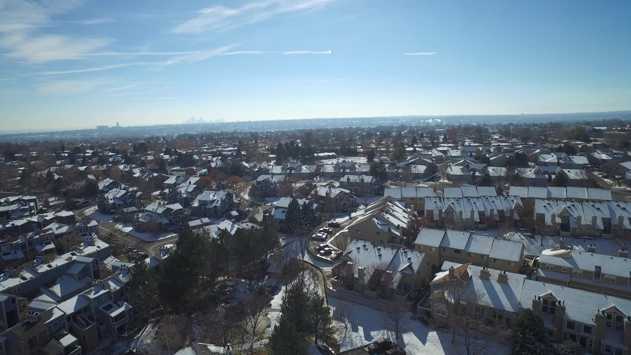 Aerial view of snow-covered suburban roofs under a blue sky.