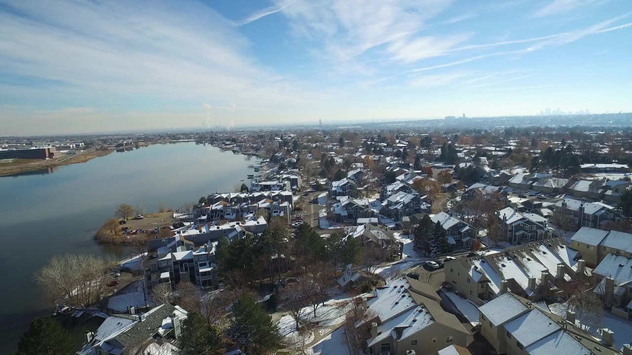 Hidden Lake, Colorado appears from above with the water stretching toward the horizon, homes packed along the right shoreline, snow on roofs and lawns, and no clearly visible people.