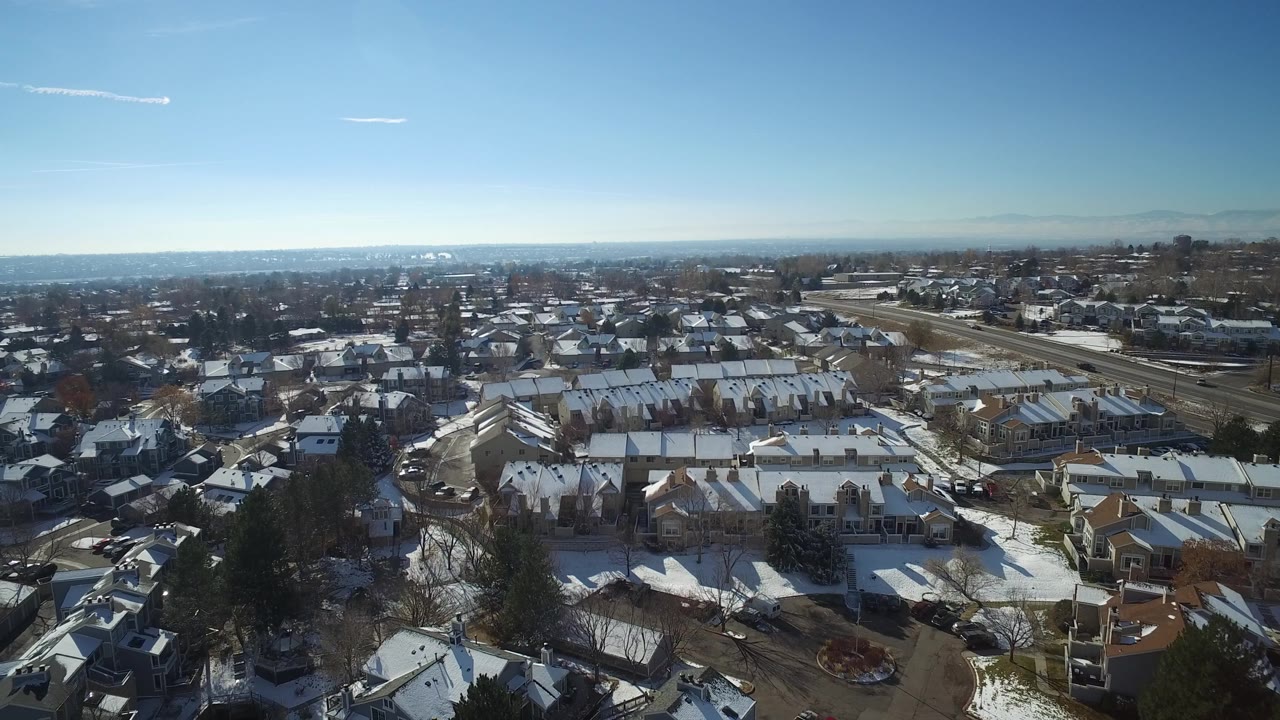 Aerial view in Hidden Lake, Colorado with rows of snow-covered homes, curved streets, a road corridor at right, and no visible people.