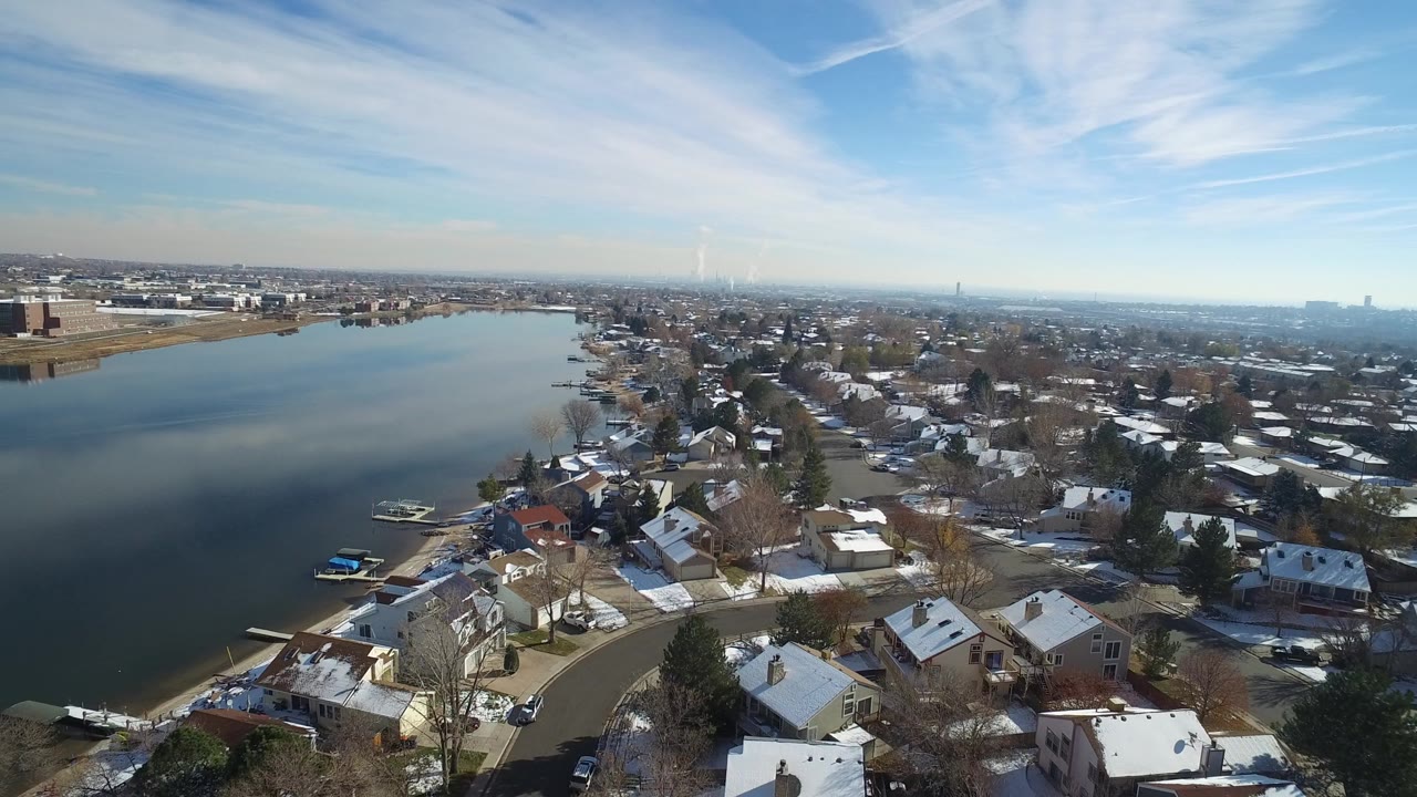 Aerial view of Hidden Lake, Colorado with calm water on the left, snow-dusted houses and bare trees along the shoreline, and no clearly visible people.