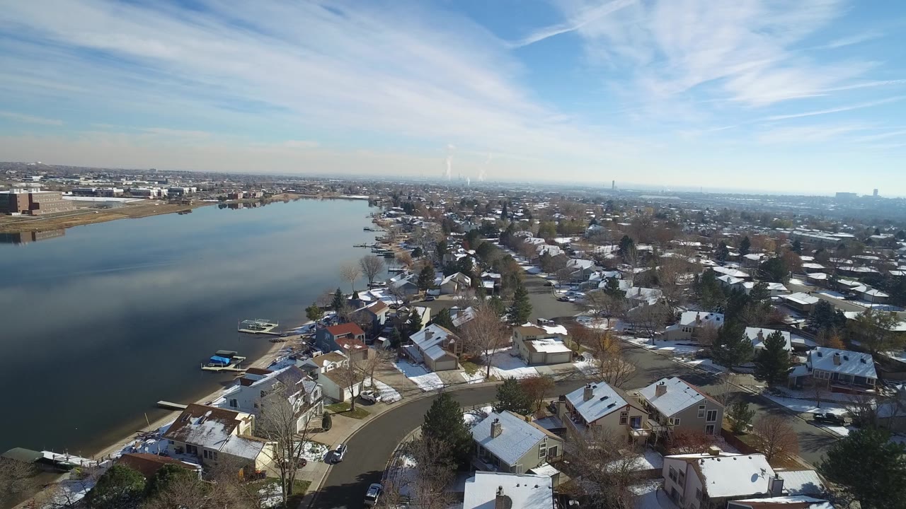 Drone-style view across Hidden Lake, Colorado with the water widening through the frame, houses clustered on the near shore, and no clearly visible people.