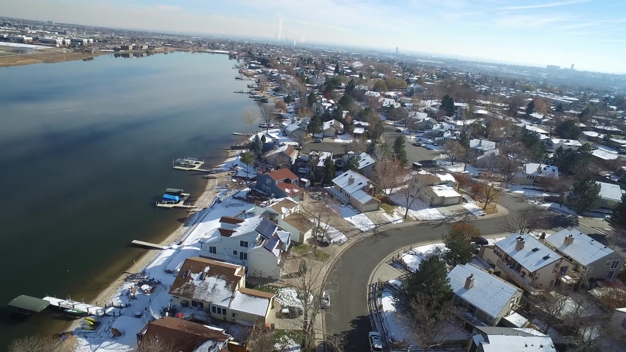 Hidden Lake, Colorado aerial view with the shoreline running diagonally, several small docks at the water, snow on roofs and yards, and no discernible people.