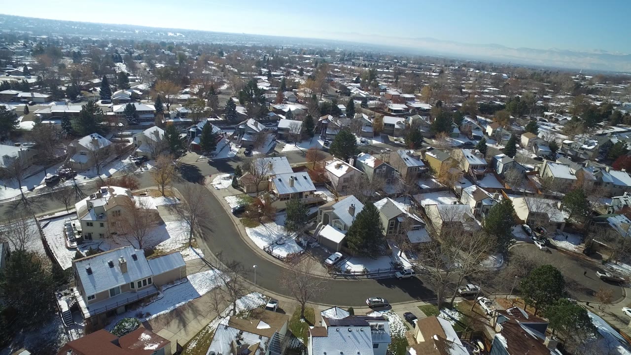 Aerial view over snowy residential streets and houses