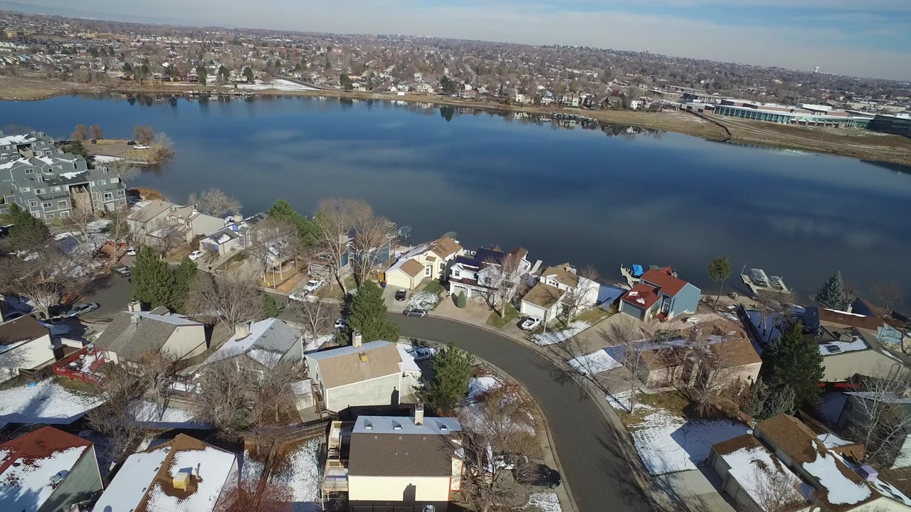 Aerial view of snow-dusted homes beside a broad lake.