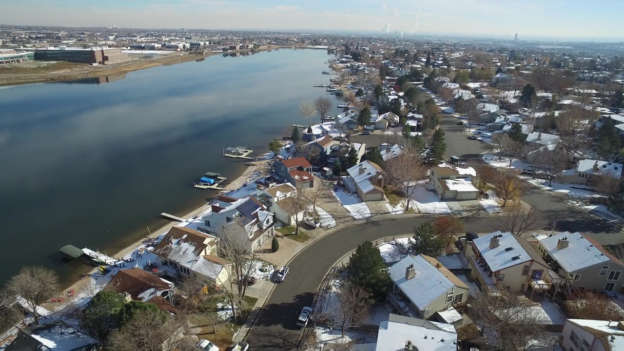Aerial view of a lakeside residential neighborhood with snow on rooftops and yards.
