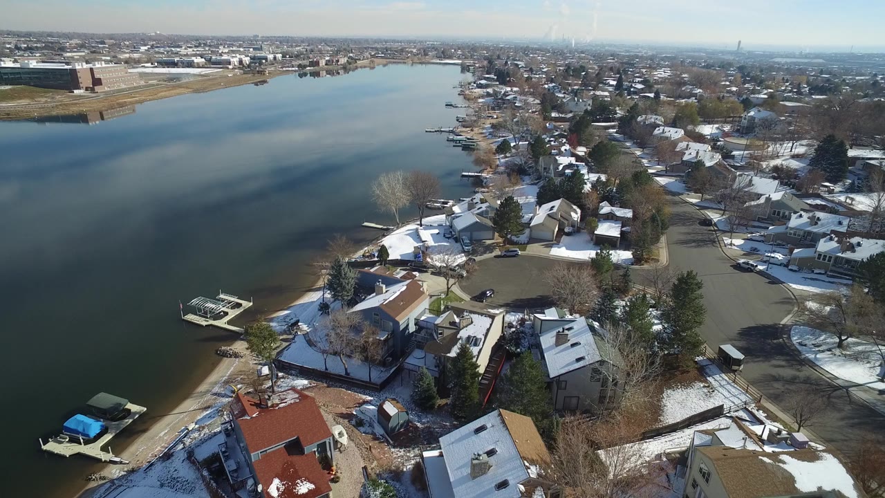 Aerial view of a lake beside snow-dusted homes and docks.