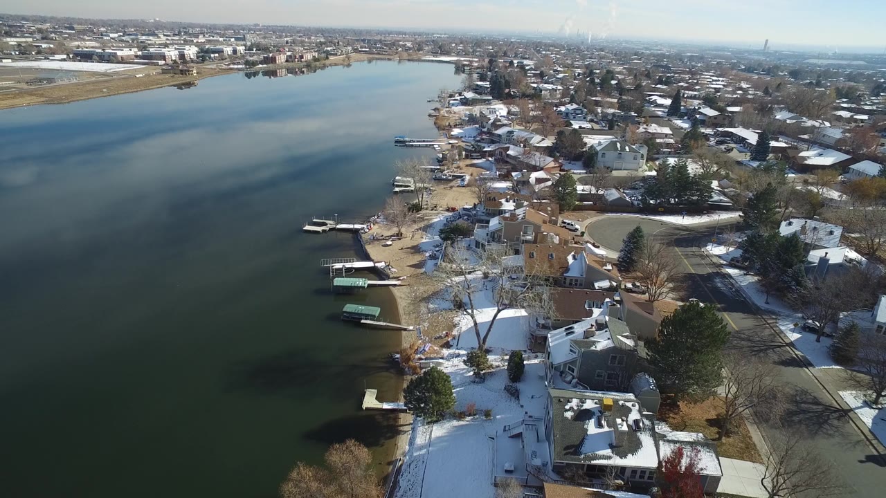 High aerial view of lake water, docks, houses, and winter trees.