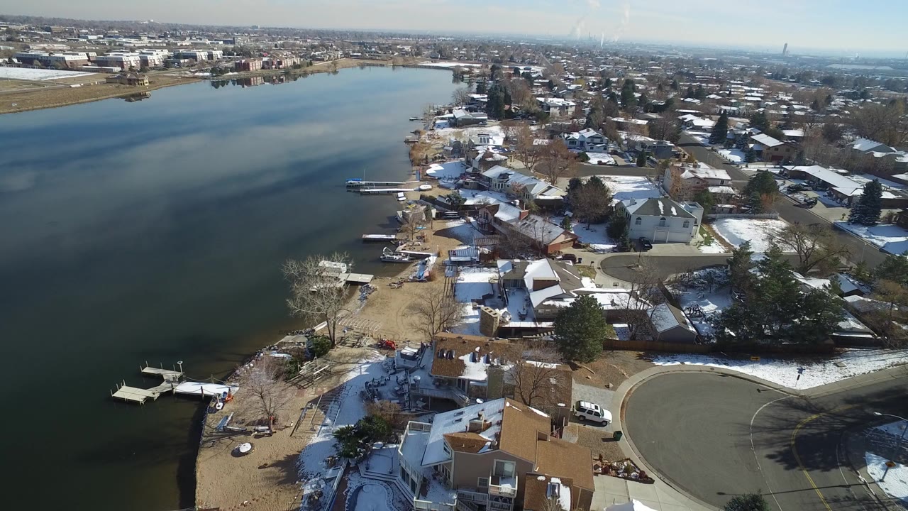 Aerial view of lake shoreline with snow-dusted homes and docks.