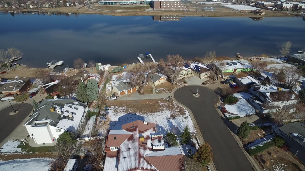 Aerial frame of a snowy residential block beside a broad waterway.