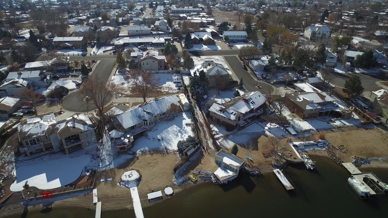 Aerial view of snowy lakefront homes and a residential street.