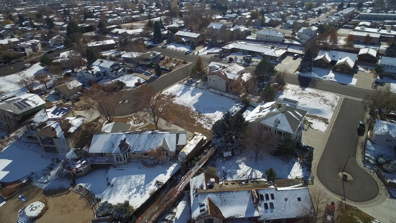 Aerial view of snow-dusted suburban homes and a curved residential street.