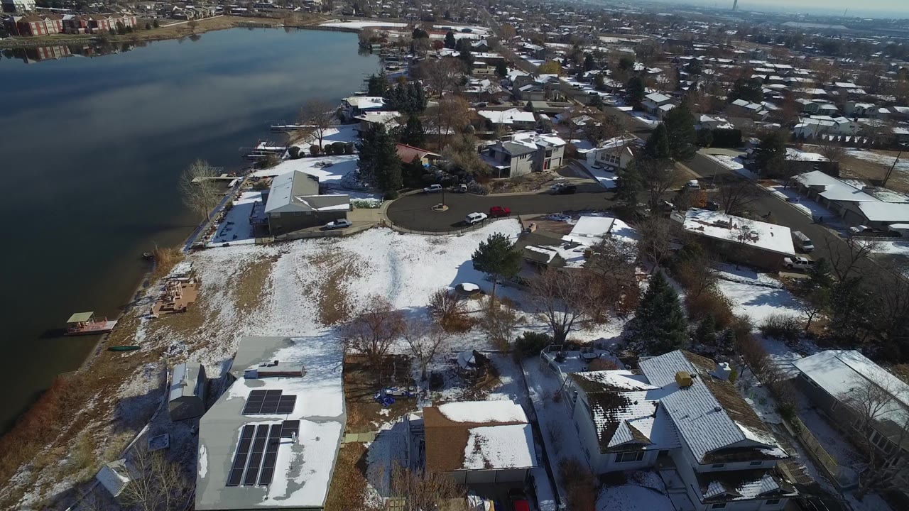 Snowy lakeside lots with homes, docks, and a circular street.