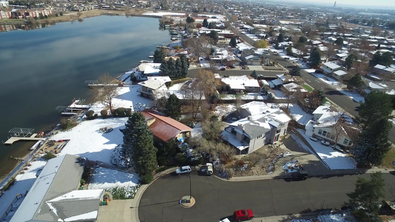 Aerial view of snowy homes beside a large pond.