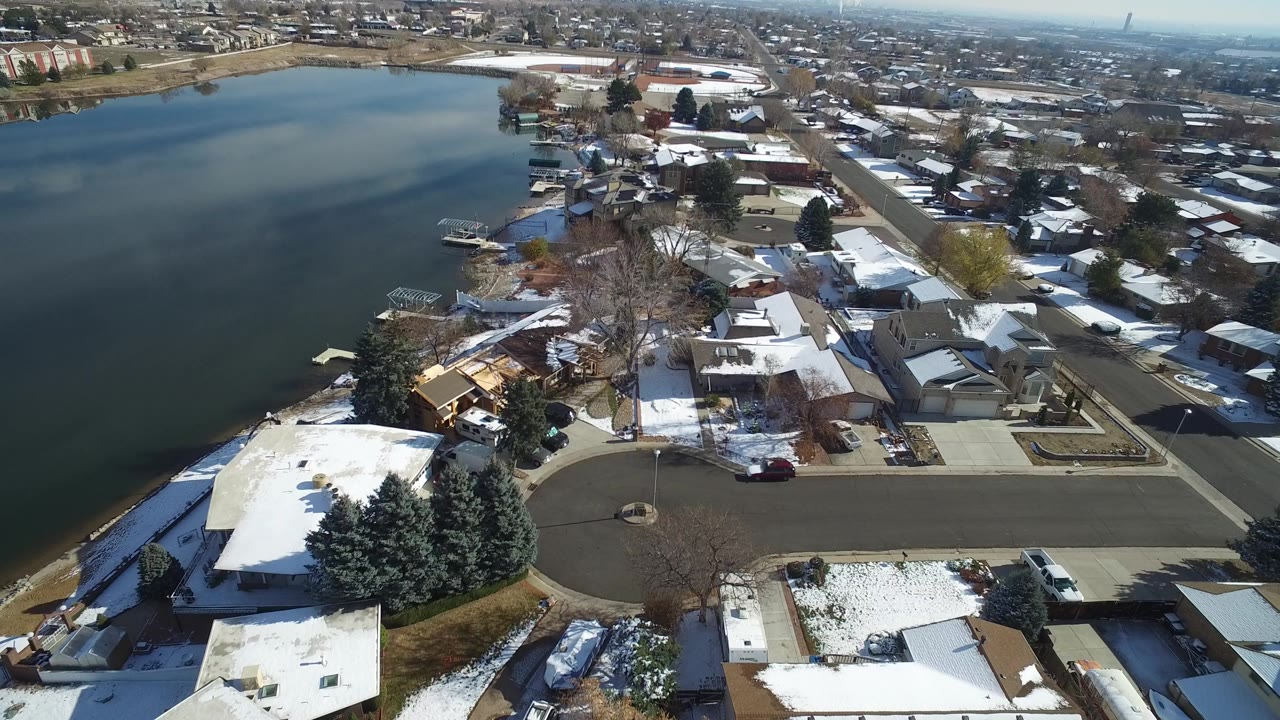 Aerial view of a snowy neighborhood beside a lake.