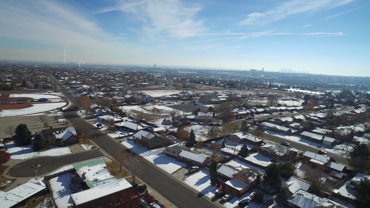 Snowy suburban neighborhood seen from above with roads and distant skyline