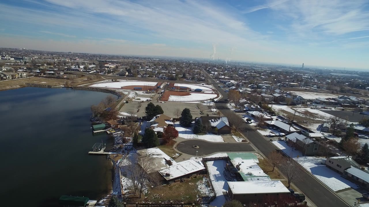 Aerial view of a lake beside snowy homes and roads