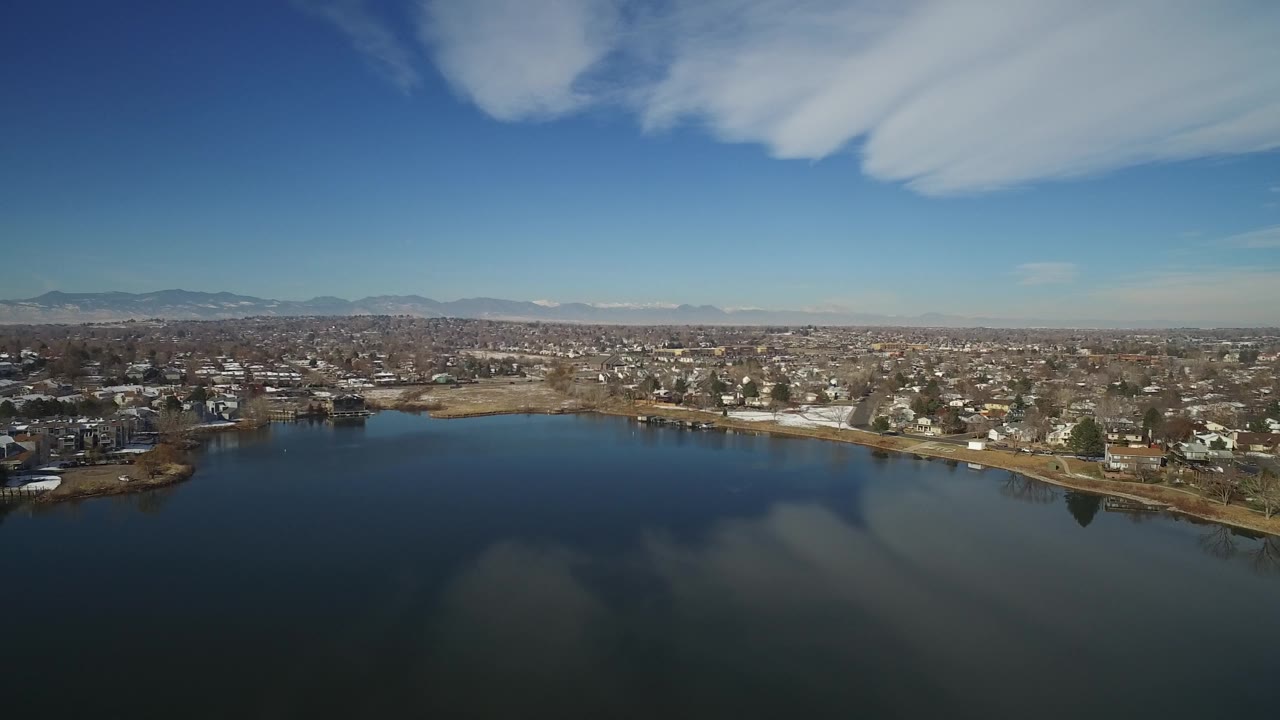 Lakefront residential neighborhood seen from above under a blue sky.