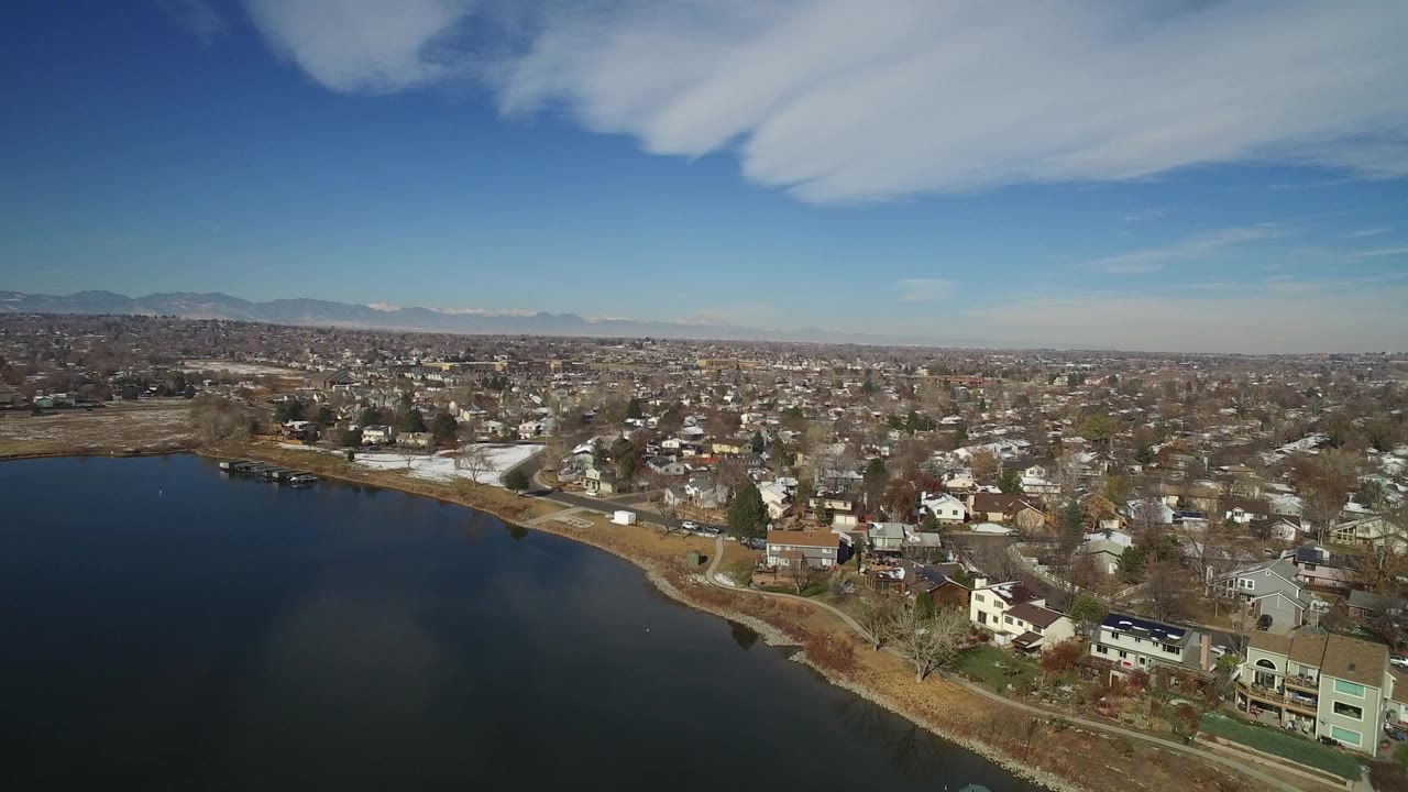 Aerial view of a lake beside a residential neighborhood under blue sky.