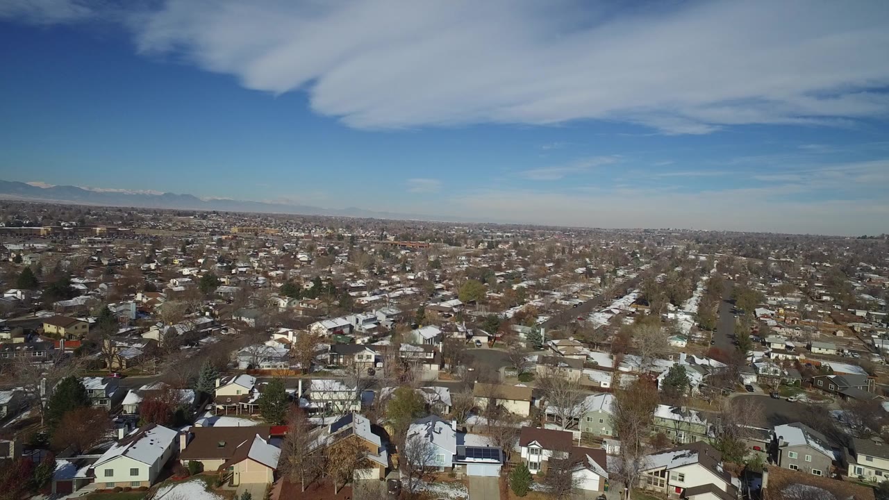 Aerial view over a residential neighborhood under a blue sky.