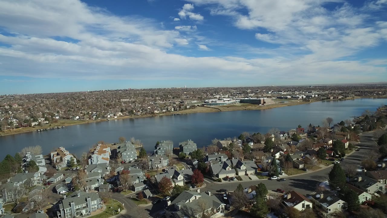 Aerial view in Westminster, Colorado with rooftops in the foreground, the lake across the middle, distant suburbs on the horizon, and no visible people.